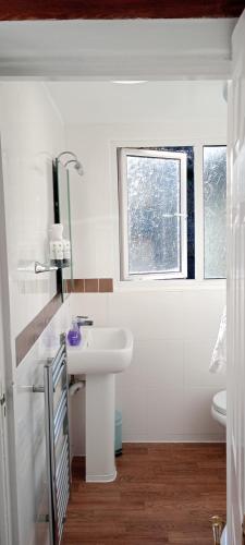 a white bathroom with a sink and a window at Durham House in Beer