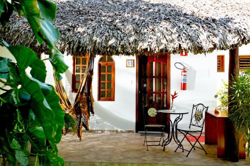 uma pequena casa branca com telhado de palha em Pousada Villa Caju em Jericoacoara