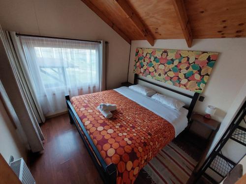 a small bedroom with a bed with a painting on the wall at Cabanas Turismo Don Ambrosio in El Manzano