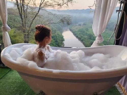 a woman sitting in a bath tub with a view at Doi Sang Farm Stay - ดอยซางฟาร์มสเตย์ in Ban Huai Kom