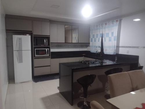 a kitchen with a black counter and a refrigerator at Alugo casa para Show Rural in São Domingos