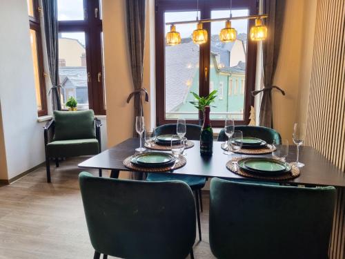 stół jadalny z zielonymi krzesłami i oknem w obiekcie maremar - Design Maisonette Altstadt - 4 Personen - Luxus Boxspringbett - Vollausstattung w mieście Greiz