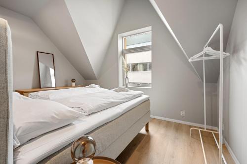 een witte slaapkamer met een bed en een raam bij Homerentals l 120sqm Mid-central - King beds - 500Mbps WI-FI in Bergen