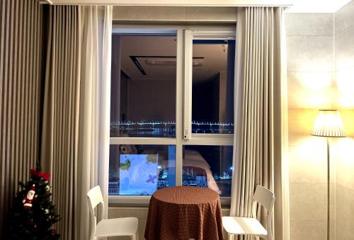 a room with a table and a window with a christmas tree at 라비앙즈-Raviens-Elliy's Room in Busan
