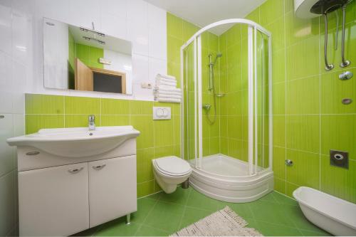 a green bathroom with a sink and a toilet and a shower at Apartments Tomić in Vodice