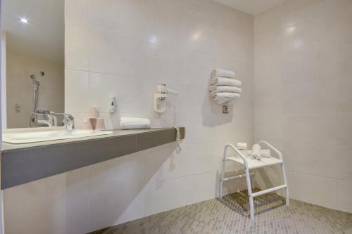 a bathroom with a sink and a mirror and towels at Brit Hotel Lille Centre in Lille