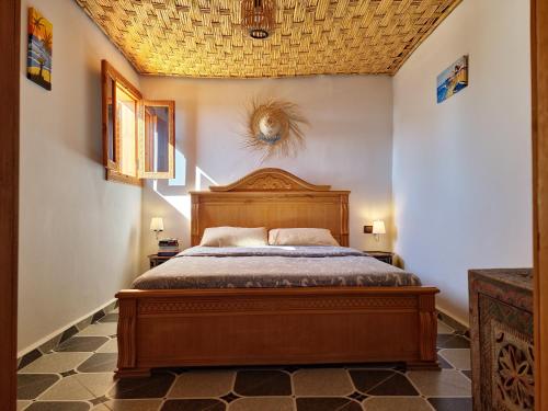 een slaapkamer met een houten bed in een kamer bij Surf hostel Morocco in Tamraght Ouzdar