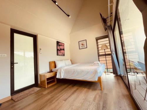 a bedroom with a bed and a large window at ROSE Villas & Resort - Ba Vi in Hanoi