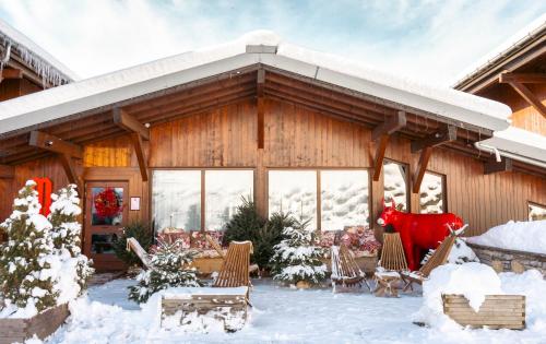 Una cabaña en la nieve con una estatua de ciervo rojo en Mamie Megève, en Megève