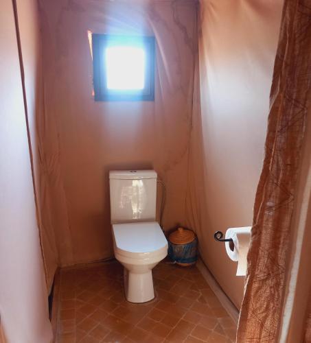 a small bathroom with a toilet with a window at Night sky luxury camp in Hassilabied