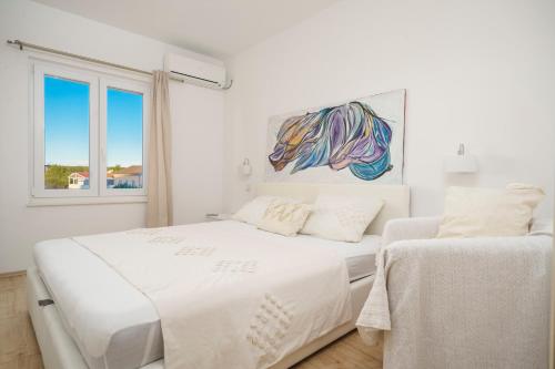 a white bedroom with a bed and a window at Apartments Tomić in Vodice