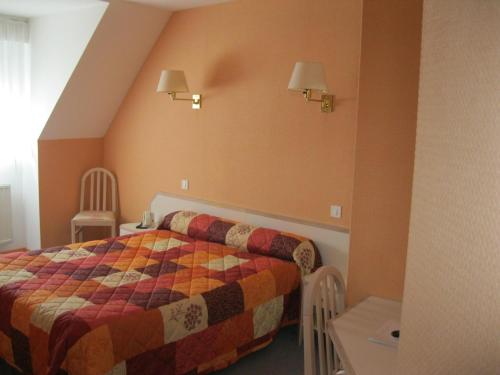 une chambre avec un lit, une table et des chaises dans l'établissement Maison Hôtel Aux Cerisiers, à La Forêt-Fouesnant