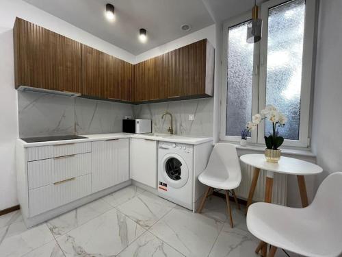 a kitchen with a washing machine and a table at Sukiennicza Residence Old Town in Gdańsk