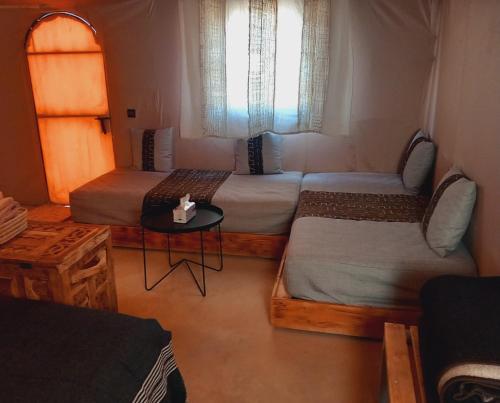 Cette chambre comprend 2 lits, une table et une fenêtre. dans l'établissement Night sky luxury camp, à Adrouine