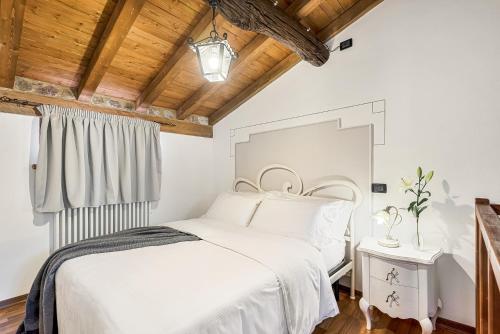 ein Schlafzimmer mit einem weißen Bett und einer Holzdecke in der Unterkunft Vivi Luxury Country House in Comano