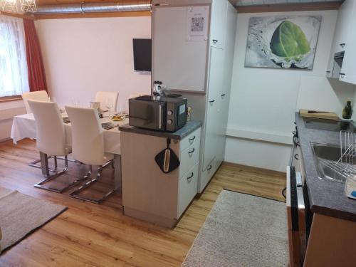 eine Küche und ein Esszimmer mit einem Tisch und einer Mikrowelle in der Unterkunft Klein aber fein in Escholzmatt