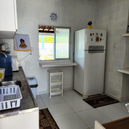 a kitchen with a white refrigerator and a window at CASA EM SERRAMBI in Porto De Galinhas