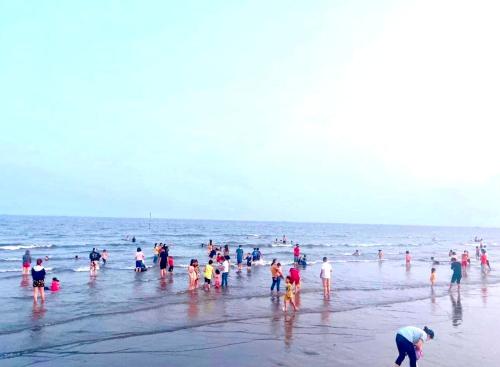 a group of people standing in the water at the beach at HaiAu Hotel in Quất Lâm