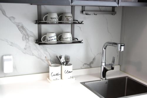 a kitchen counter with a sink and cups and utensils at Elliy's Room in Busan