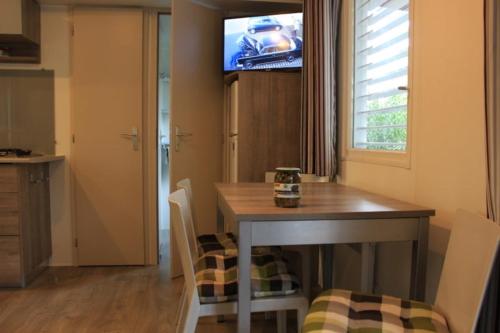 的住宿－Mobilheim 4-5 Personen MH9，一间设有桌子和墙上电视的用餐室