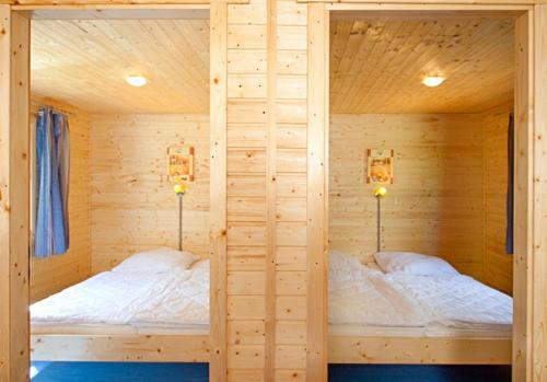 two beds in a wooden cabin with two lamps at Ferienhaus 4 Personen FH6 