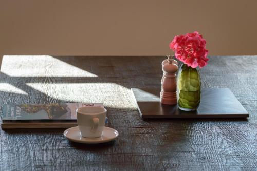 a table with a coffee cup and a vase with flowers at DAS SALZBERG Hideaway Bad Aussee - Adults only in Bad Aussee