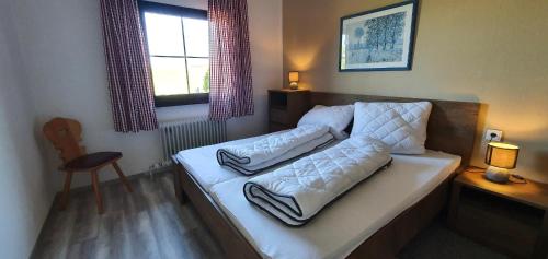 Schlafzimmer mit einem Bett mit weißer Bettwäsche und einem Fenster in der Unterkunft Lechbruck am See Feriendorf Hochbergle Haus 7 in Lechbruck