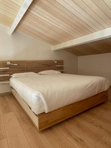 een slaapkamer met een groot bed met een houten hoofdeinde bij APPARTEMENT DUPLEX PORTICCIO Centre in Porticcio