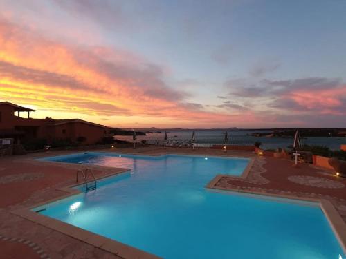 une grande piscine avec un coucher de soleil en arrière-plan dans l'établissement MONOLOCALE STUDIO Zia Make, à Marinella