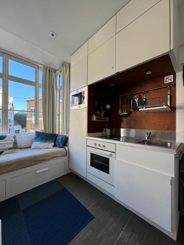 une cuisine avec des armoires blanches et un évier dans l'établissement Maison Belle Rade : La Balise, à Malo-les-Bains