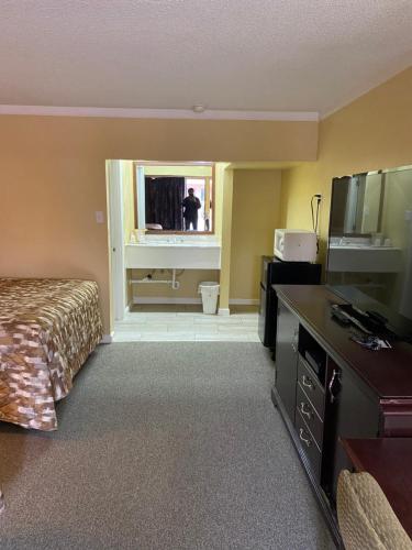 una habitación de hotel con una cama y una persona en el espejo en Caronoda Motel, en Central City