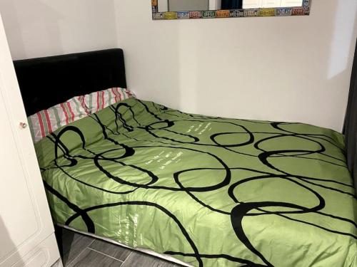 a bedroom with a bed with a green comforter at Charmante maisonnette au calme in Neuilly-en-Thelle