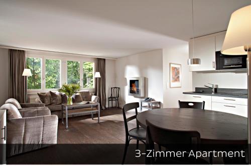 a kitchen and a living room with a dining room table at Hotel Arc-en-ciel Gstaad in Gstaad