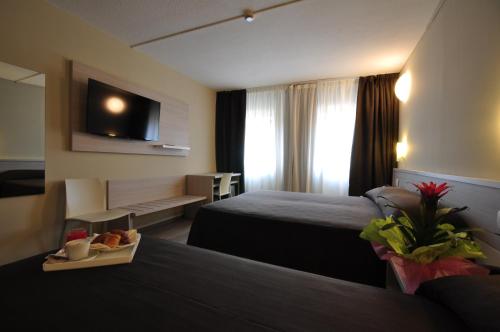 a hotel room with two beds and a television at Best Quality Hotel Politecnico in Turin