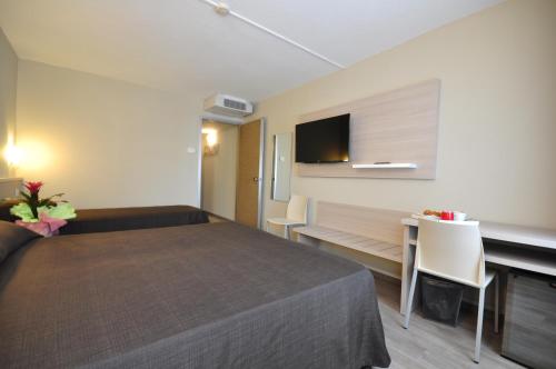 a hotel room with a bed and a desk and a tv at Best Quality Hotel Politecnico in Turin