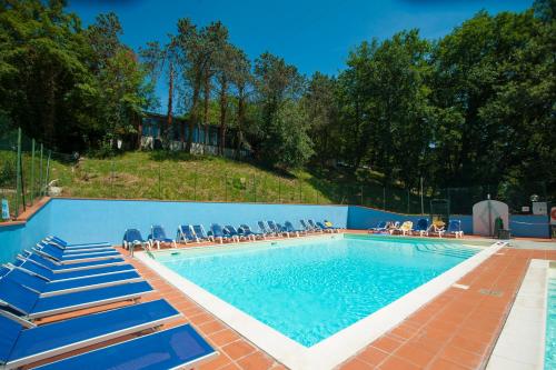 una piscina con sillas azules y gente sentada a su alrededor en Firenze Certosa camping, en Impruneta