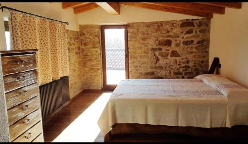- une chambre avec un lit et un mur en pierre dans l'établissement Case Apuane, à Minucciano