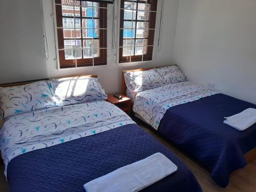 Zimmer mit einem Bett, einem Bett und Fenstern in der Unterkunft Casa Hotel Palermo 49 in Bogotá