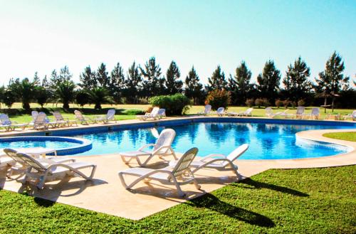 a group of lawn chairs and a swimming pool at Wyndham Garden Campana in Campana