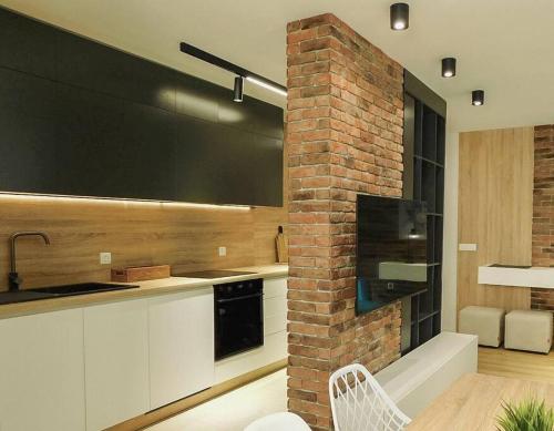 una cocina con armarios blancos y una pared de ladrillo en Queen's luxury Apartment, en Ohrid