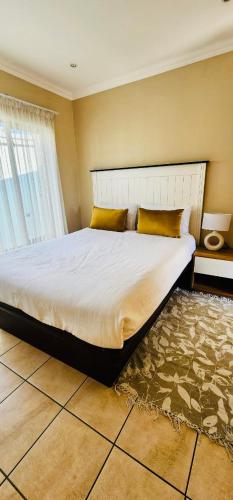 ein Schlafzimmer mit einem großen Bett mit gelben Kissen in der Unterkunft A Warm 3 bed Townhouse in a secure complex in Witbank