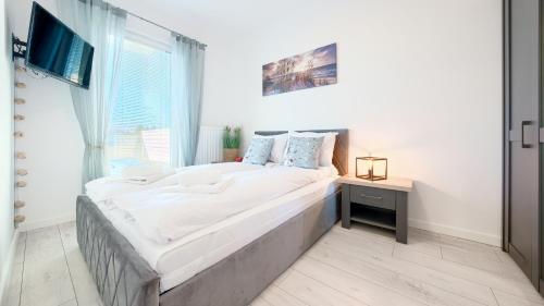 ein großes Bett in einem Zimmer mit einem großen Fenster in der Unterkunft Apartamenty Sun & Snow Pelikan in Rewal