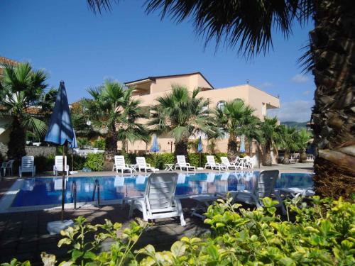 una piscina con sedie e palme e un edificio di Apartment in Marina/Kampanien 21122 a Castellammare di Velia