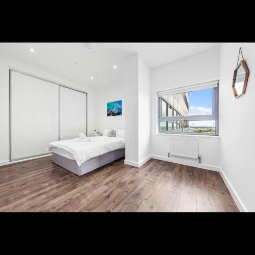 a white bedroom with a bed and a window at Delta 1 Br Apartment in London DP328 in Croydon