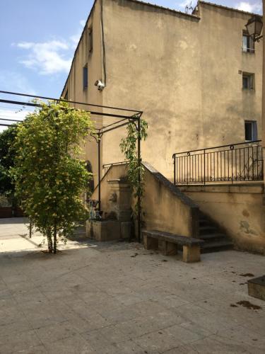 a building with a staircase and a tree next to it at Maison de village in Malaucène