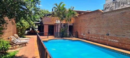 a swimming pool next to a brick wall at Nada de Tucanes. Piscina Loft in Posadas