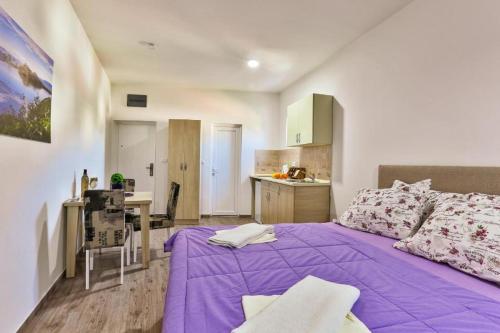 a bedroom with a purple bed and a kitchen at Buskovic Bella Vista in Dobra Voda
