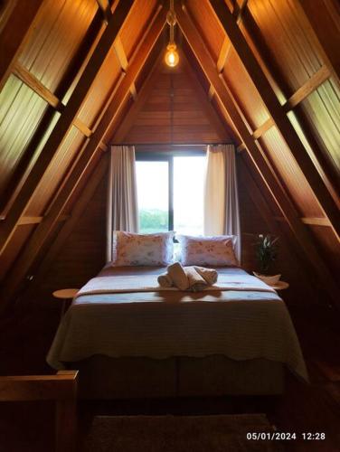 a bed in a room with a window at Cabana com hidro e natureza! in Estefânia