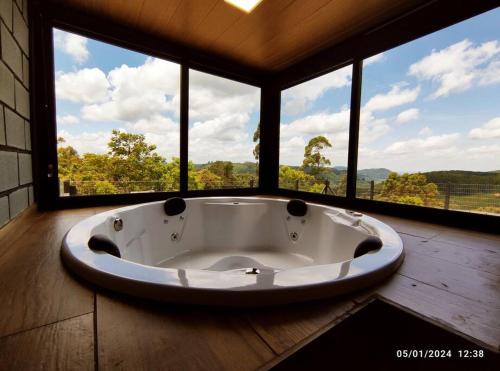 Habitación con bañera grande y ventanas grandes. en Cabana com hidro e natureza!, en Estefânia