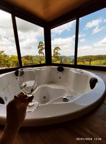 a person holding a glass of wine in a bath tub at Cabana com hidro e natureza! in Estefânia